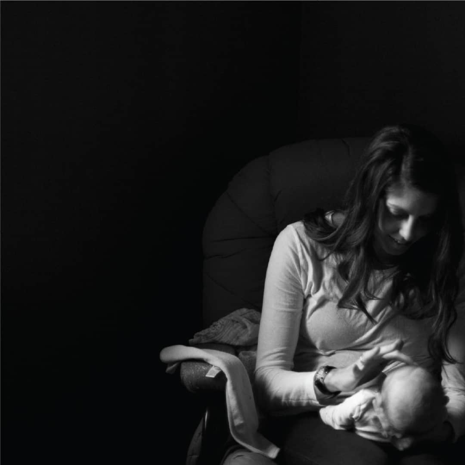 Mother sitting on a chair in a dark room holding her baby