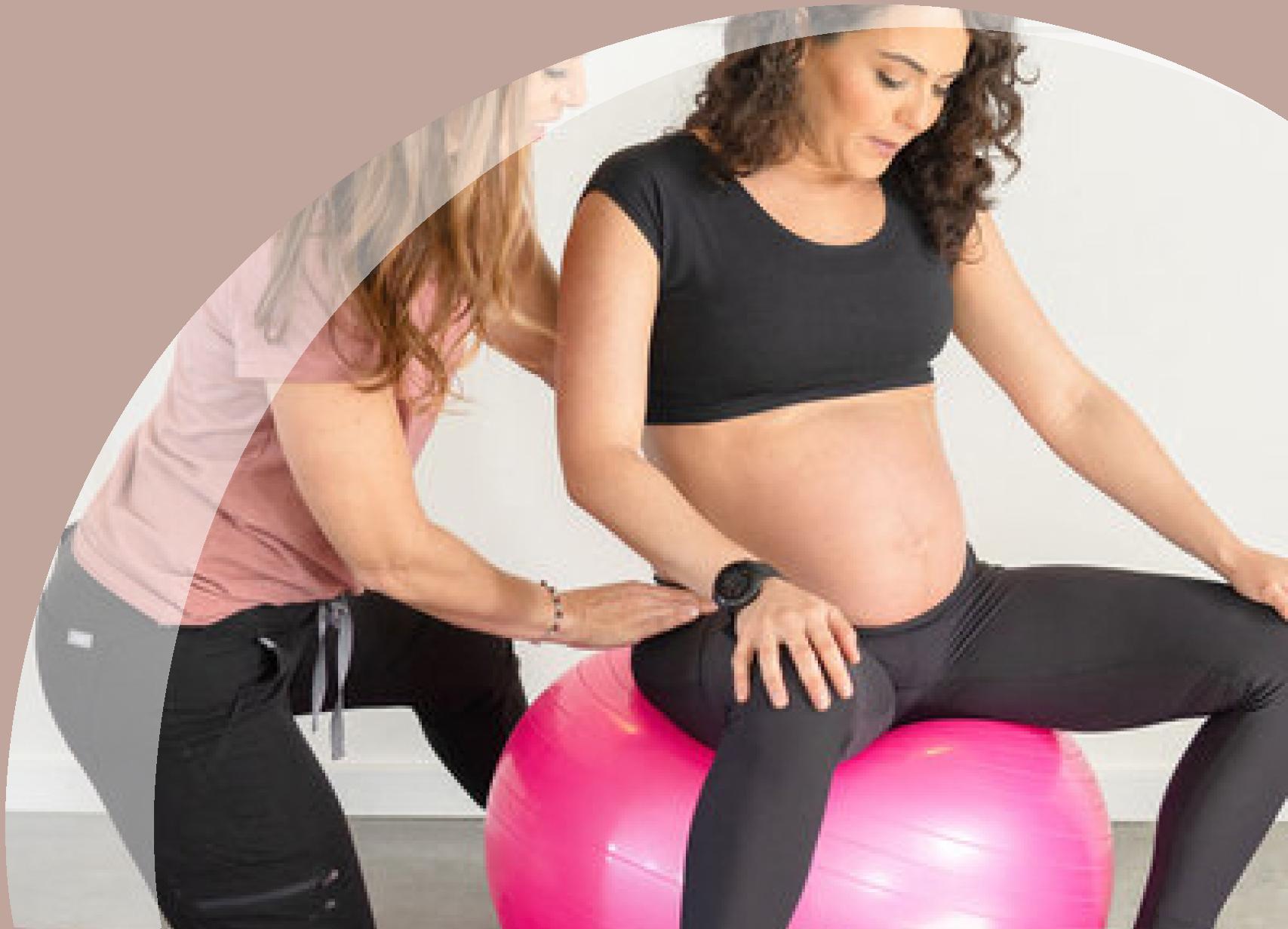 Trainer working with a pregnant woman sitting on a yoga ball
