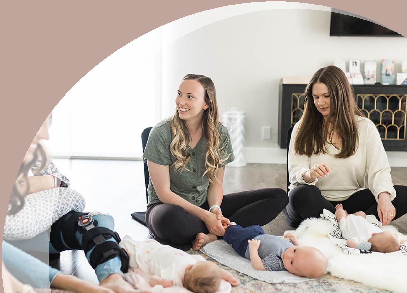 Group of smiling moms sitting with babies on blankets out in front of them on the floor