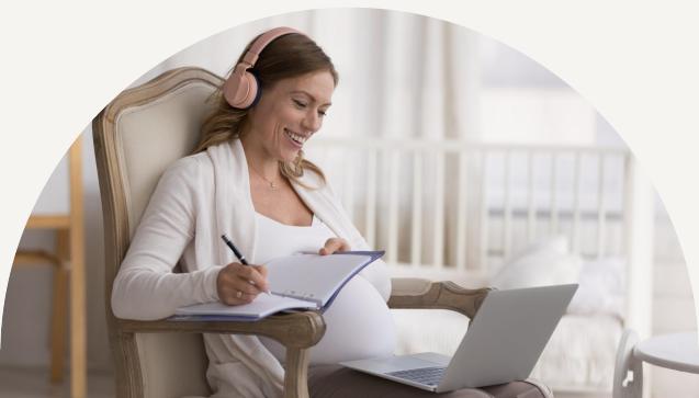 A pregnant mother wearing headphones sitting in a chair while studying