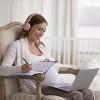 Pregnant woman wearing headphones sitting in a chair studying