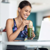 smiling woman in workout gear drinking a smoothy