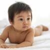 Small cute infant doing tummy time on a white bed